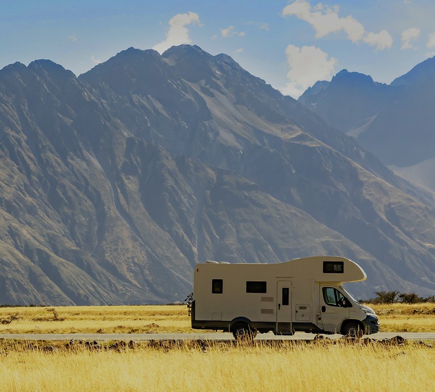 A white campervan parked below a mountain range